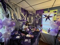 a room filled with purple and white balloons, streamers and stars on the wall