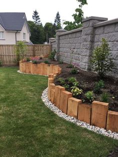 a garden with rocks and grass next to a brick wall on the side of a house