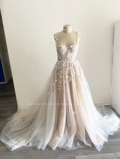 a wedding dress is displayed on a mannequin in front of a white wall