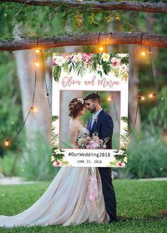 a wedding photo frame with lights hanging from the branches and flowers on it, next to a bride and groom