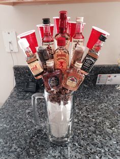 a glass vase filled with liquor bottles on top of a counter