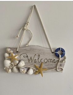 a welcome sign hanging from the side of a wall with seashells and starfish