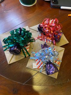 three wrapped gift bows on top of brown envelopes with candy in the bottom one