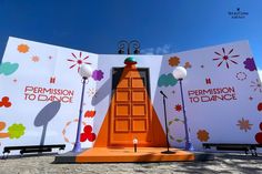 an orange door is in front of two large billboards with the words permission to dance on them