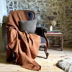 a chair with a blanket draped over it in front of a stone wall and floor