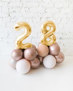 the number twenty two balloons are stacked on top of each other in front of a white brick wall