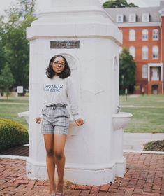 a woman standing in front of a white monument with her hands on her hips and looking at the camera