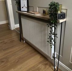 a white radiator sitting on top of a wooden floor next to a plant