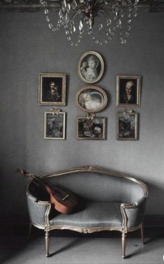 an old couch in front of a wall with pictures on it and a guitar propped up against the wall