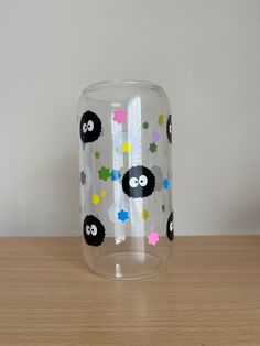 a clear glass with black sheep and stars painted on the side, sitting on a wooden table