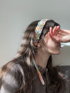 a woman with long hair wearing a headband and holding her hand up to the side