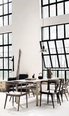 a dining room table and chairs in front of large windows with lots of light coming through them