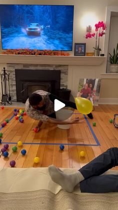 a man is sitting on the floor with balls in front of him and watching tv