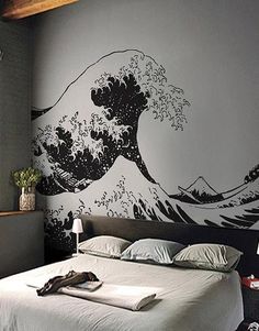 a bed sitting under a window next to a wall with a wave painted on it