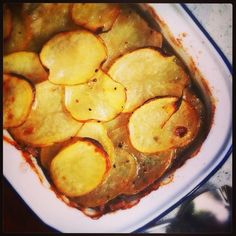 a casserole dish filled with potatoes and sauce