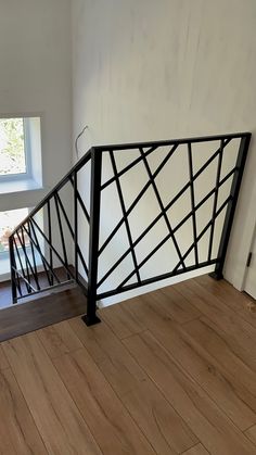 an empty room with wood flooring and black iron handrails on the stairs