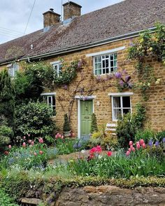 an old stone house with flowers growing on it