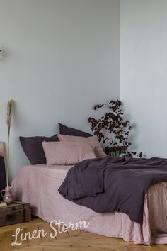 a bed sitting in a bedroom next to a wooden table with a potted plant on top of it