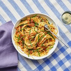 a white bowl filled with pasta on top of a blue and white checkered table cloth