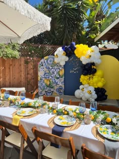 the table is set with yellow and white balloons