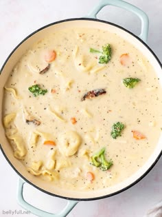 a pot filled with pasta and broccoli on top of a white countertop