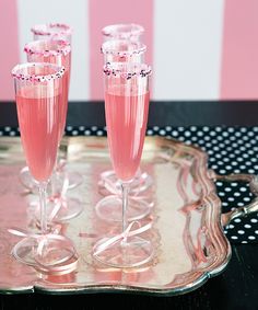 three champagne flutes sitting on top of a metal tray