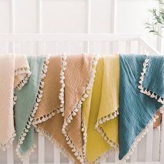 a row of towels hanging from the side of a crib in front of a potted plant