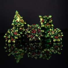 several small green and red objects sitting on top of a black surface with water reflection