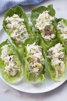 several lettuce leaves with chicken salad on them sitting on a plate next to a blue towel