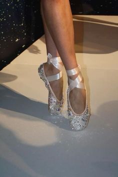 a close up of a person's feet wearing ballet shoes with glitter on them