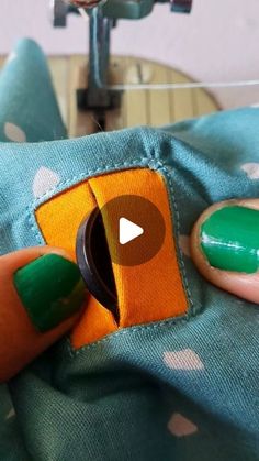 a person with green and orange nail polish on their nails holding a piece of fabric