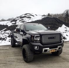 a large black truck parked in front of a mountain