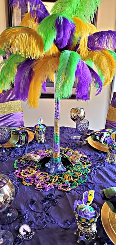 a table topped with purple, green and yellow feathers on top of a blue table cloth