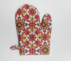 an oven mitt with red, yellow and blue designs on the front sitting on a white surface