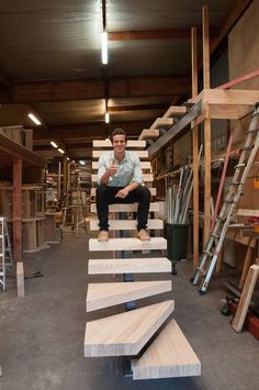 a man sitting on top of wooden steps in a garage next to shelves and ladders