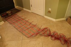 a red and white plaid blanket laying on the floor in front of a door that is being taped down