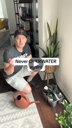 a man sitting on the floor holding up a sign that says never overwater again