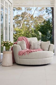 a living room with a round couch and large windows