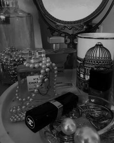 black and white photograph of chandelier, perfume bottles, and other items on a bathroom sink