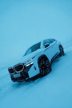 a white car is driving through the snow