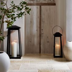 two black and white lanterns sitting next to each other on a stone floor in front of a wooden door