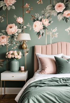 a bedroom decorated in green and pink with flowers on the wall behind the headboard