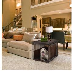 a dog is sitting in his crate on the floor next to the couch and table