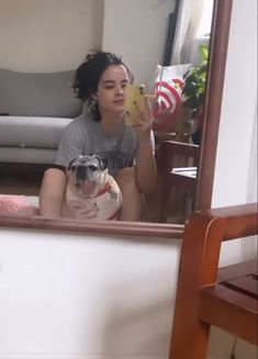 a woman sitting in front of a mirror holding a dog