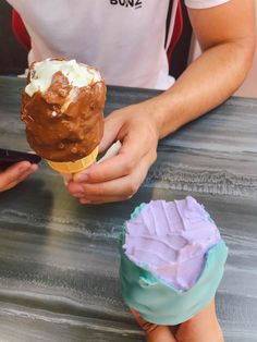 someone is holding an ice cream cone with chocolate and marshmallows on it