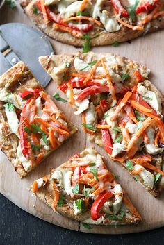 a pizza with many toppings cut into slices on a cutting board next to a fork