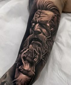 a man's arm with a black and grey tattoo on it, depicting the face of jesus