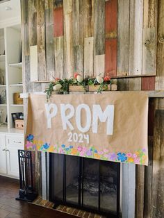 a sign that says prom hanging on a fireplace mantel in front of a wood paneled wall