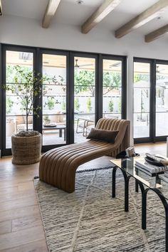 a living room with couches, tables and large windows