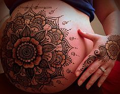 a pregnant woman's belly with henna tattoos on her stomach and the top half of her body